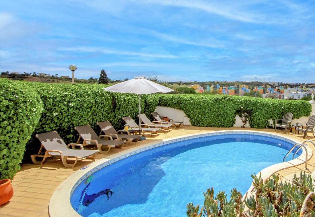 una piscina con sillas y sombrilla en Villa Ventura Marina, en Albufeira