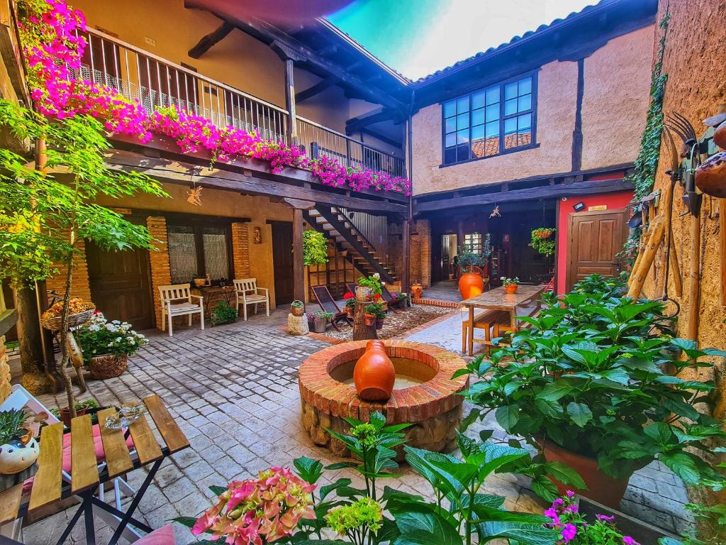 un patio con una fuente, mesas y flores en Albergue El Encanto en Villares de Órbigo