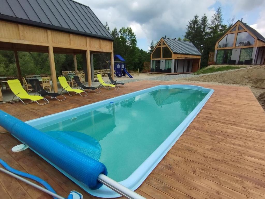 a swimming pool with chairs and a house at Stodoły Hołosanka 600-065-145 in Polańczyk