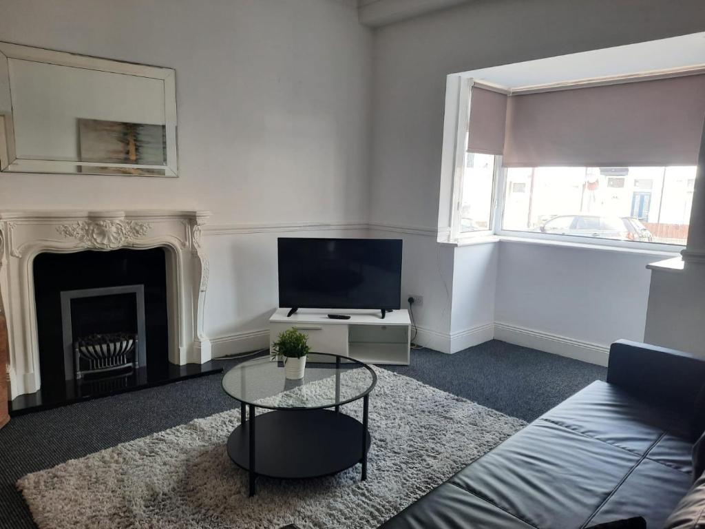 un soggiorno con divano, TV e camino di Alexander Apartments South Tyneside 2 a South Shields
