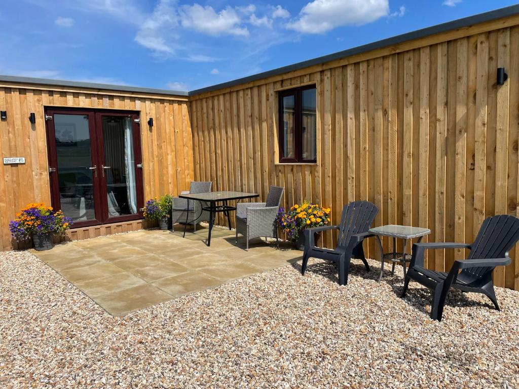 a patio with chairs and a table next to a building at Mallard s Retreat in Blandford Forum