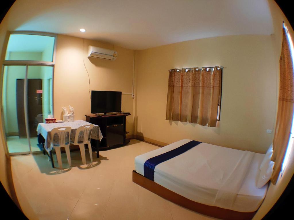 a bedroom with a bed and a table and a television at บ้านพักเรือนแก้ว แม่สรวย 2 in Ban Sam Laem