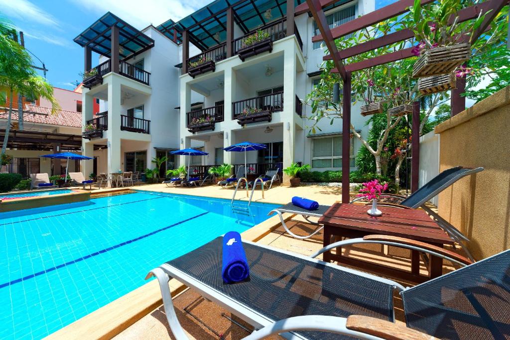 a swimming pool with chairs and a table next to a building at Krabi Apartment-SHA Extra Plus in Ao Nang Beach