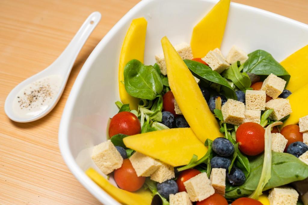 a plate of salad with fruits and vegetables on a table at Hotel dP Olbia - Sardinia in Olbia