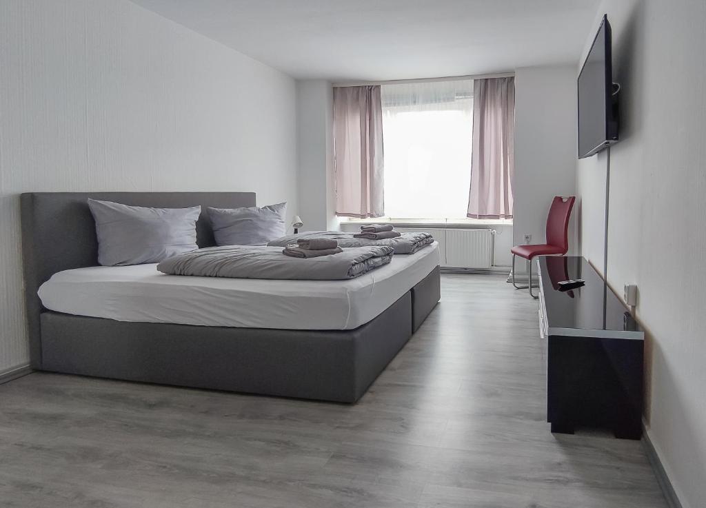 - une chambre avec un grand lit et une chaise rouge dans l'établissement Zwehrener Hof, à Cassel