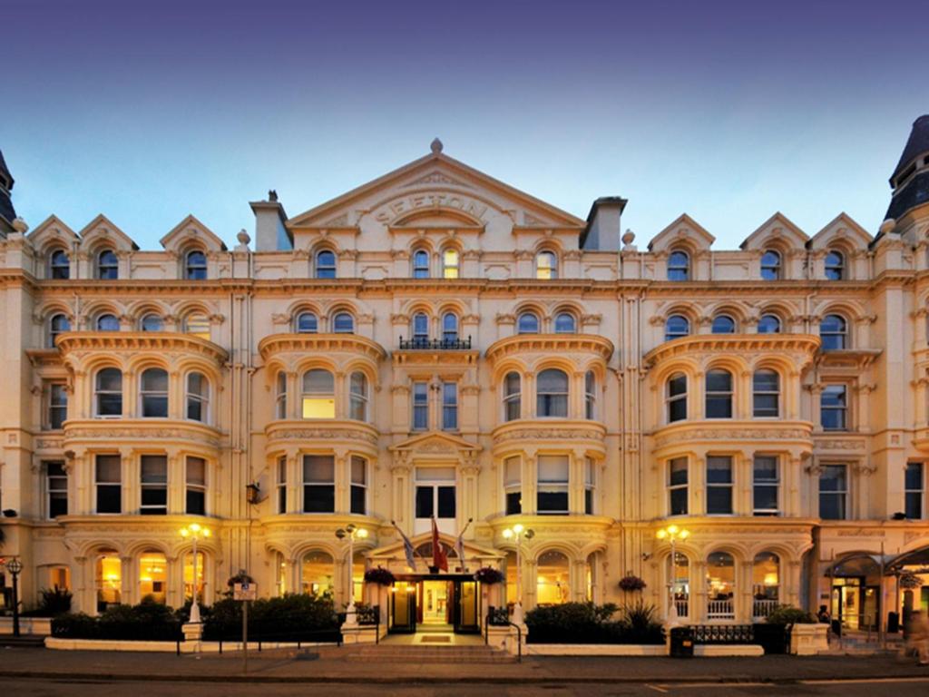 Un grand bâtiment néoclassique avec des lumières allumées dans l'établissement The Sefton, à Douglas