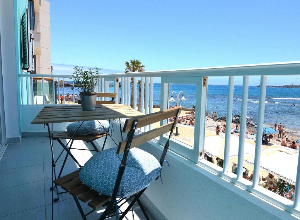 een balkon met een tafel en stoelen en het strand bij ARINAGA ARENA Y MAR BEACH in Arinaga