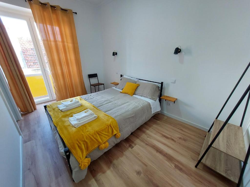 um quarto com uma cama com um cobertor amarelo em Wolley - Peniche GuestHouse 2 em Peniche