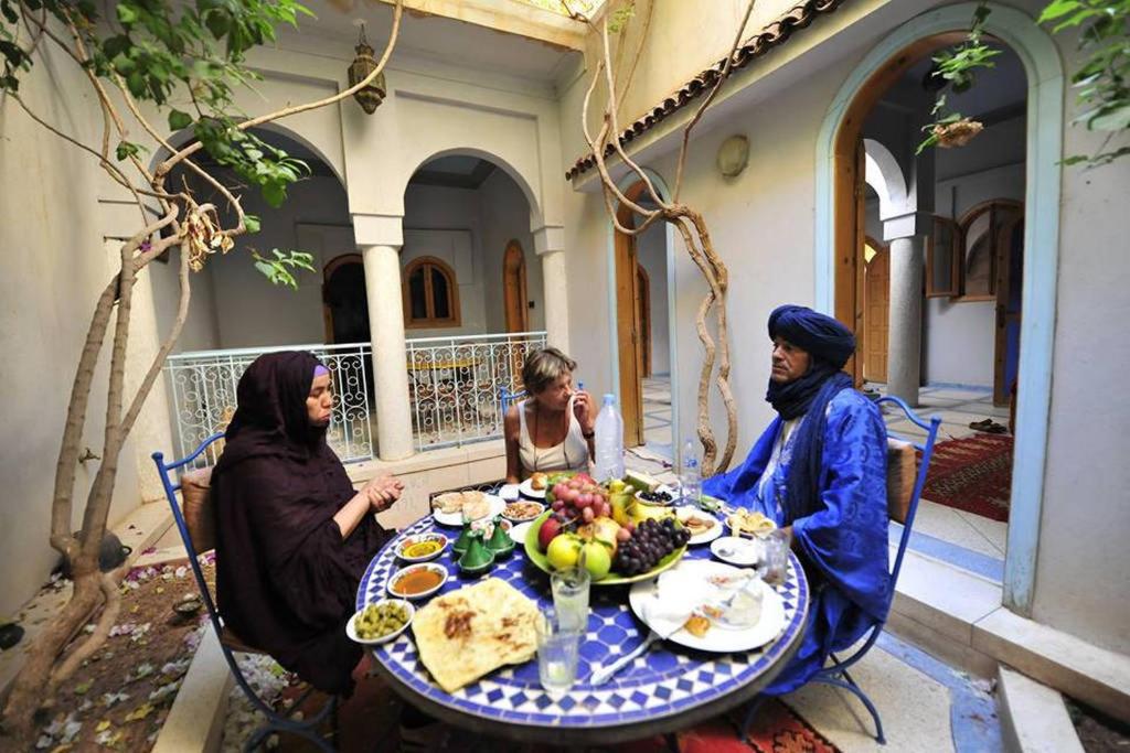 grupa ludzi siedzących przy stole z jedzeniem w obiekcie Riad De Rêve w mieście Zakura