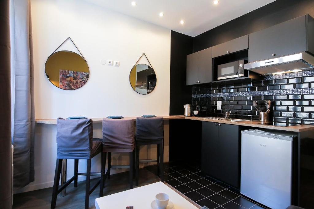 une cuisine avec des placards noirs et des tabourets bleus dans l'établissement Le Grunge, T2 hypercentre chic et cosy, Wifi par SOVALFI, à Saint-Étienne