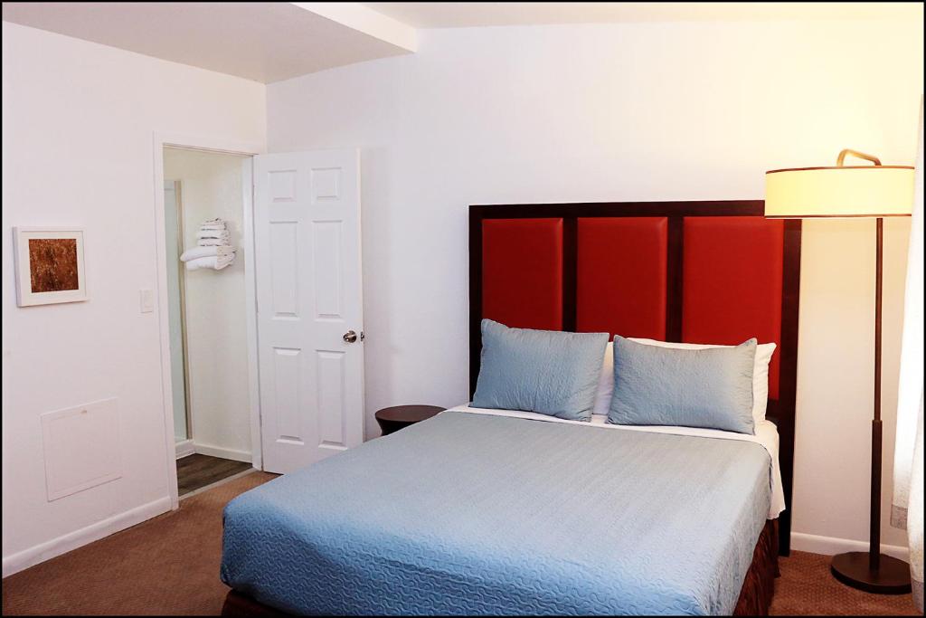 Kemmerer的住宿－Antler Motel，一间卧室配有一张大床和红色床头板