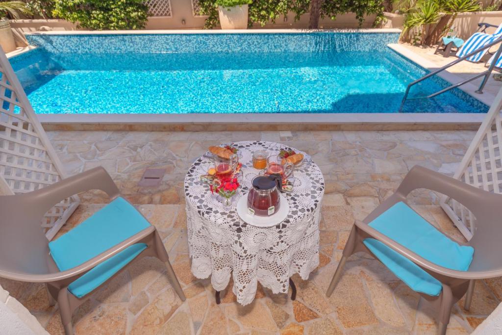 a table and chairs next to a swimming pool at Apartments Fortunella in Petrovac na Moru