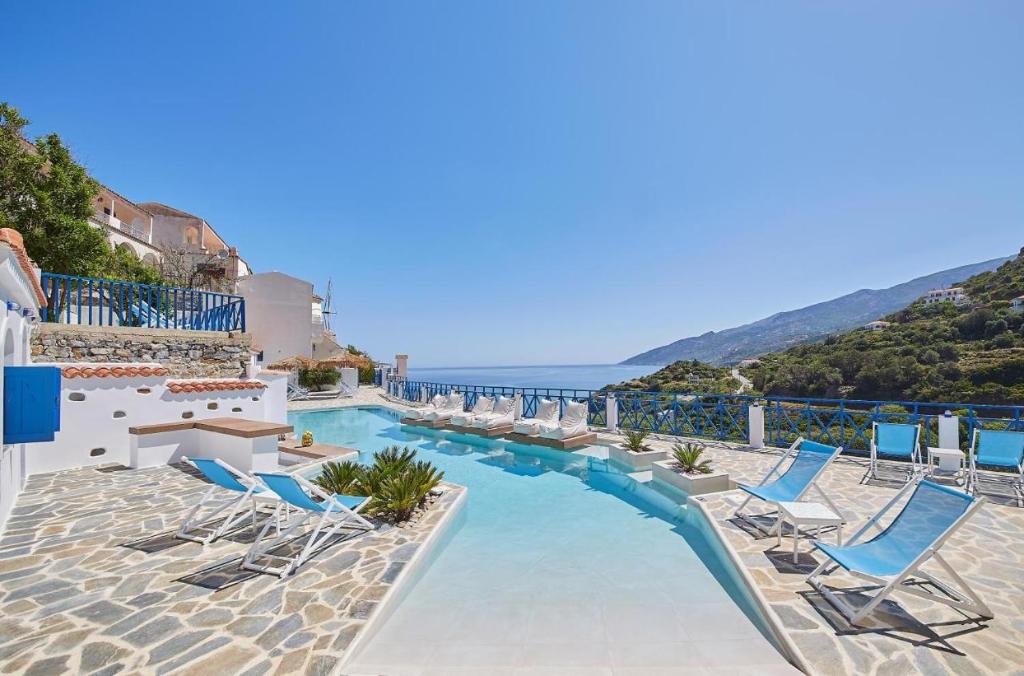 a swimming pool with chairs and the ocean in the background at Sea View Kerame in Évdhilos