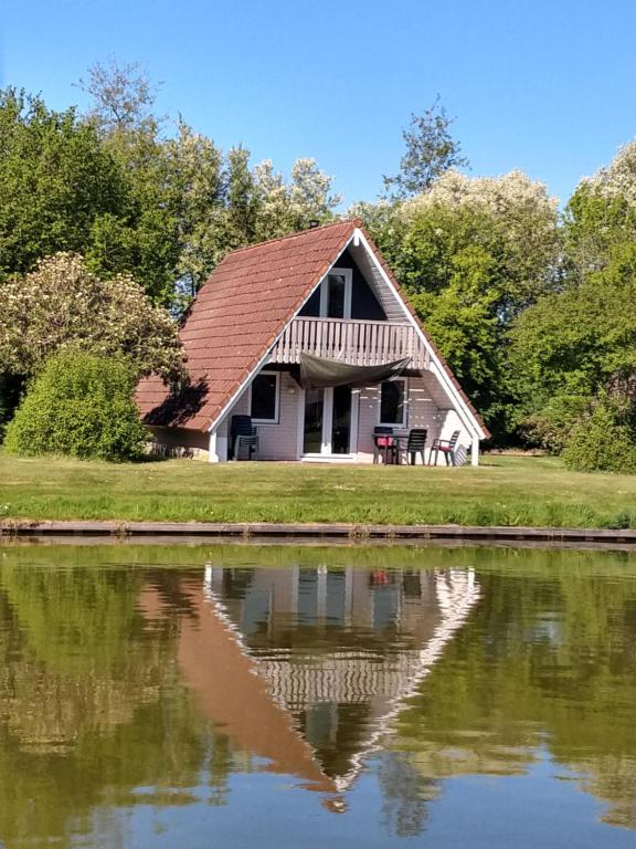 een huis met een reflectie in het water bij De Gouwe, 158 - aan visvijver, de beste visstek in Gramsbergen