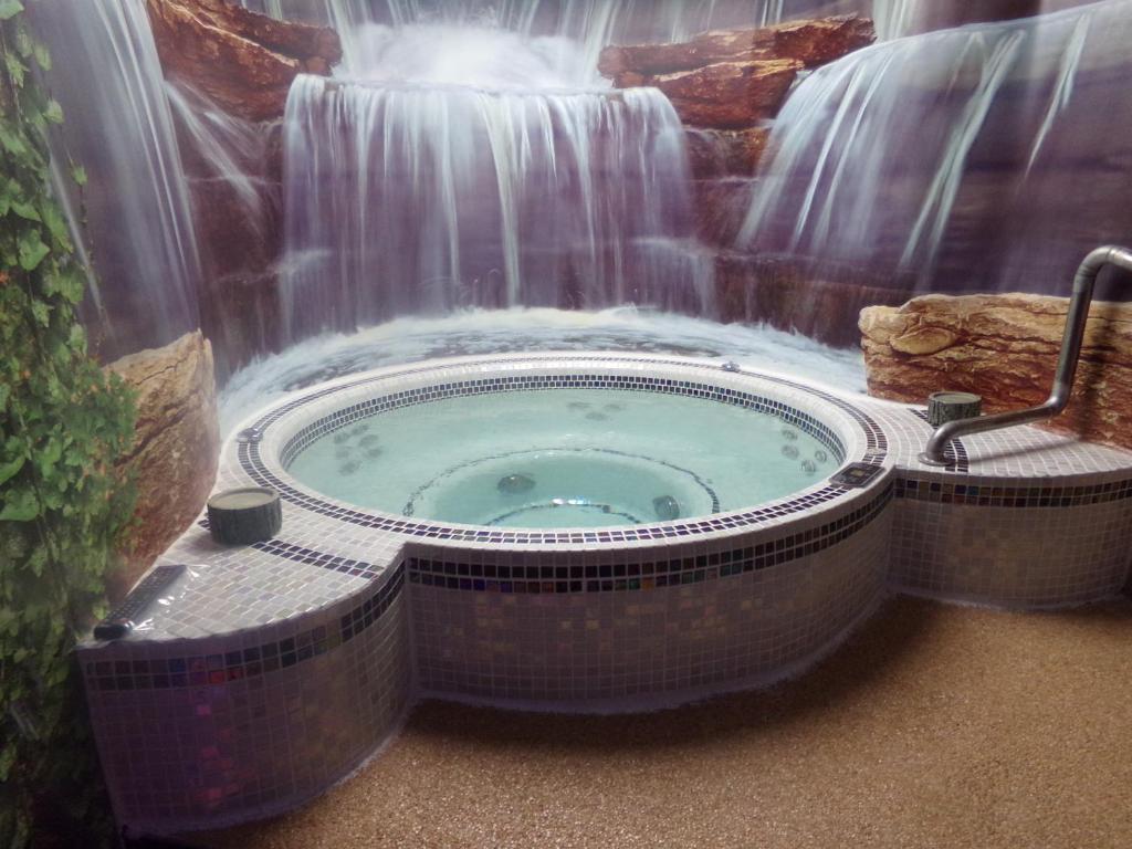 chambre avec spa privatif في لون-بلاج: حوض استحمام ساخن أمام الشلال