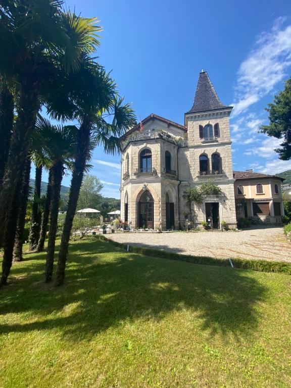 stary dom z palmą przed nim w obiekcie Castello mit Park w mieście Ponte Tresa