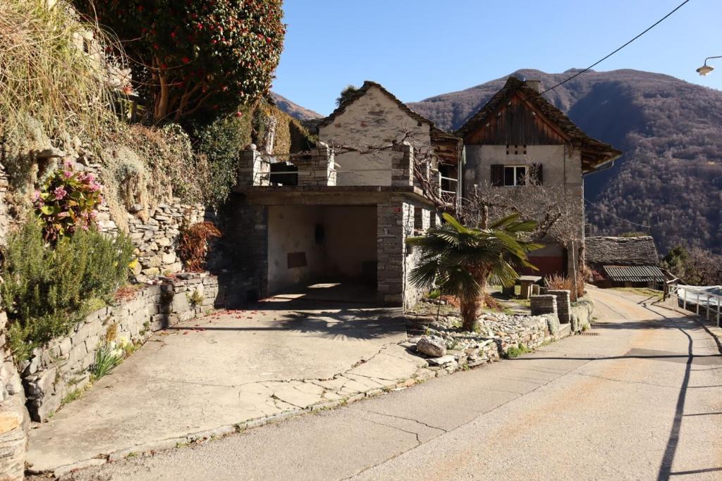 ein Steinhaus mit Garage auf einer Straße in der Unterkunft Casa Bruja Tradizionale Rustico Ticinese in Mergoscia