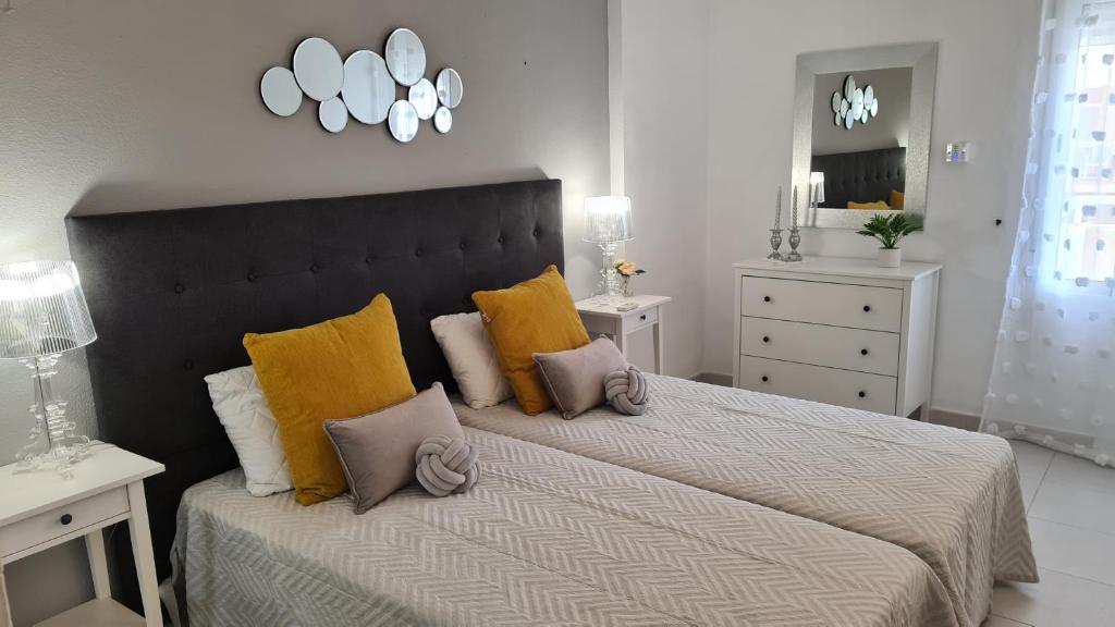 een slaapkamer met een groot bed met gele kussens bij Benalmadena JUPITER - Delux 1Bedroom Apartment in Benalmádena