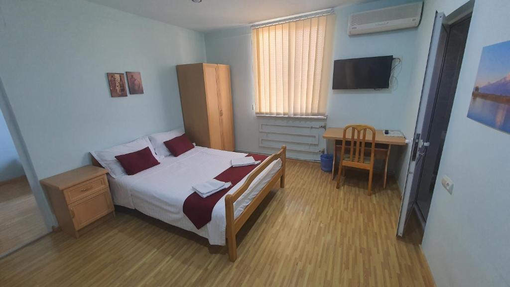 um quarto com uma cama, uma secretária e uma televisão em Kesabella Touristic House em Yerevan