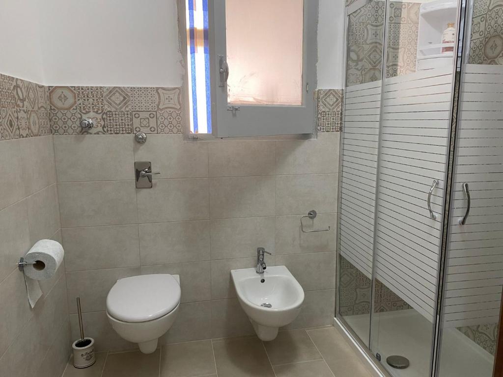 La salle de bains est pourvue de toilettes et d'une douche en verre. dans l'établissement Casa vacanze ferro, à Trapani