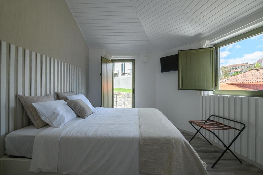 a bedroom with a white bed and a window at Casa da Torre in Amarante