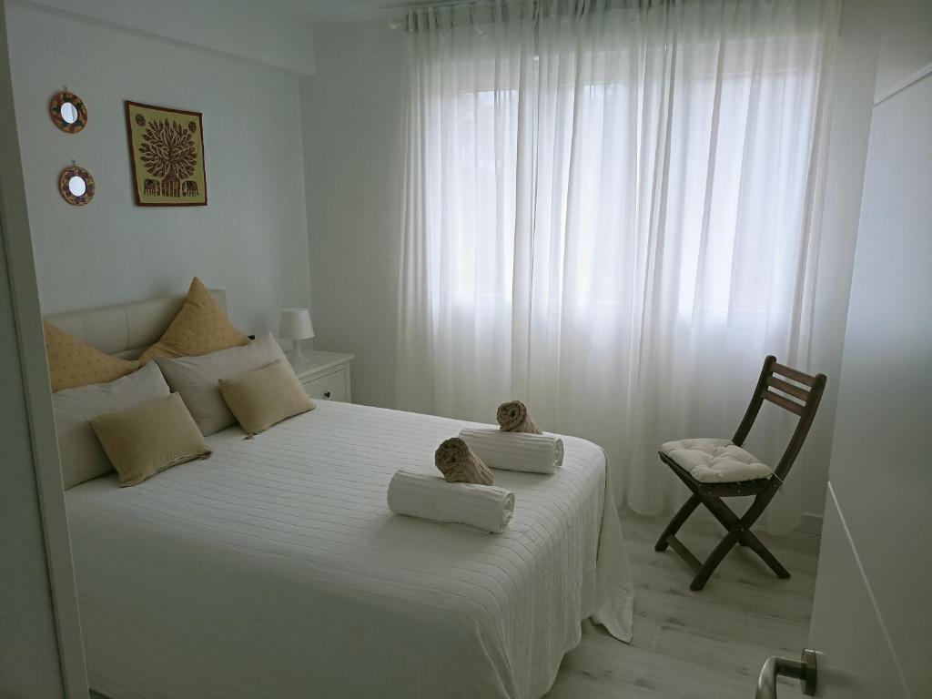 ein Schlafzimmer mit einem großen weißen Bett mit zwei ausgestopften Tieren in der Unterkunft EL RINCON DE CRISTINA in Perlora