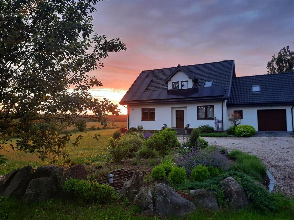 a white house with a sunset in the background at Pod Wielkim Wozem in Jerutki