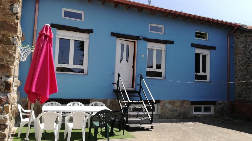 uma casa azul com uma mesa e um guarda-chuva rosa em La casa azul del Pantano em La Costana