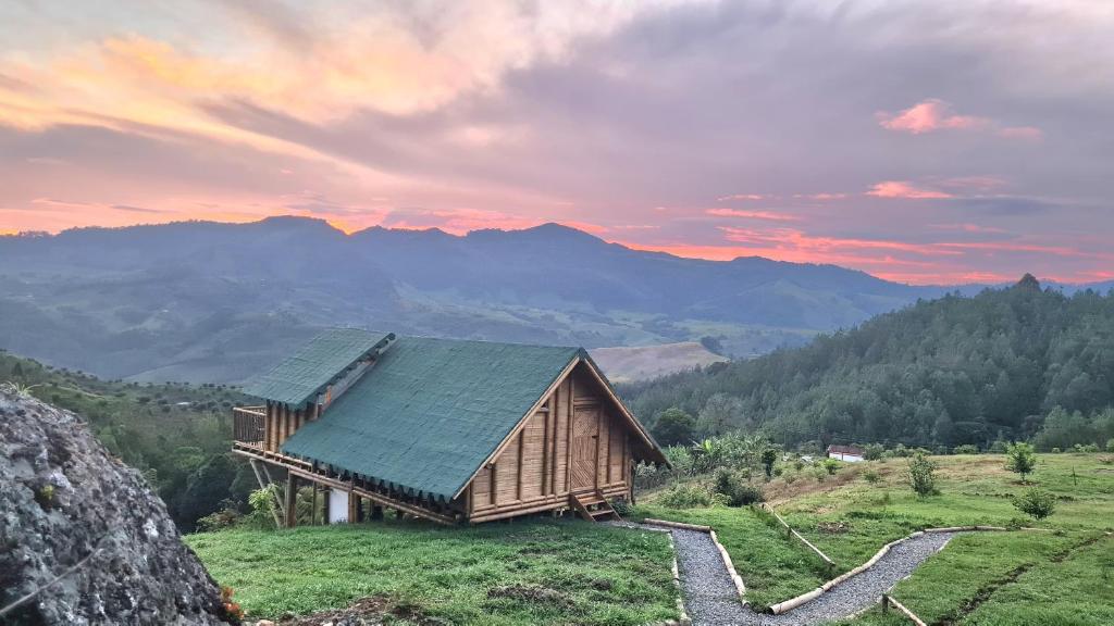 a wooden house on a hill with mountains in the background at Hass Glamping Jericó in Jericó