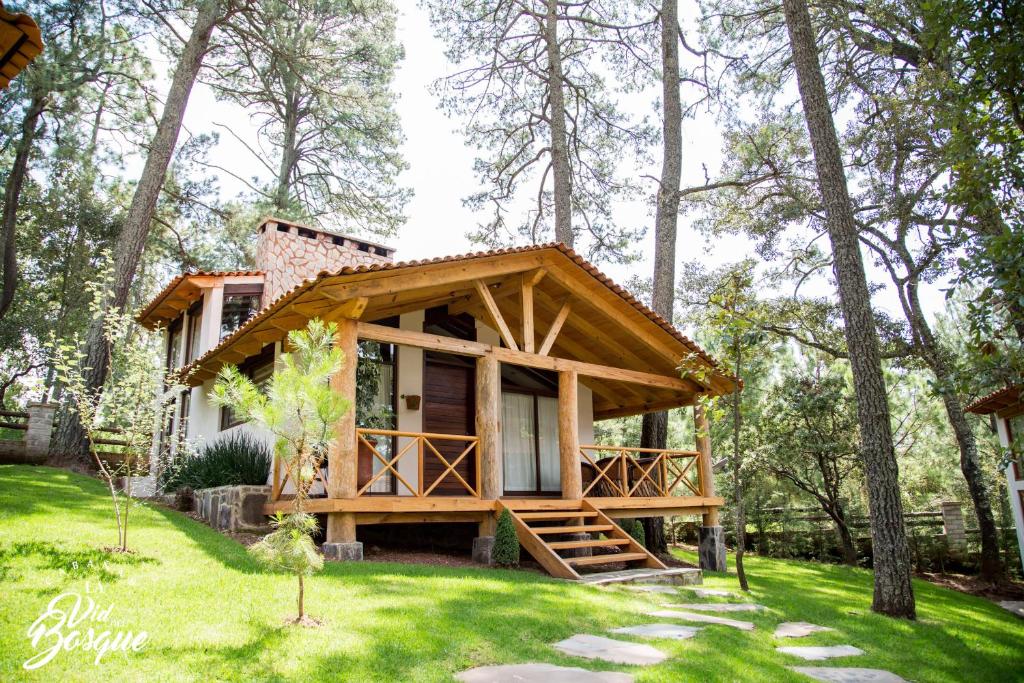 a house in the woods with a green yard at Cabañas La Vid Del Bosque in Tapalpa