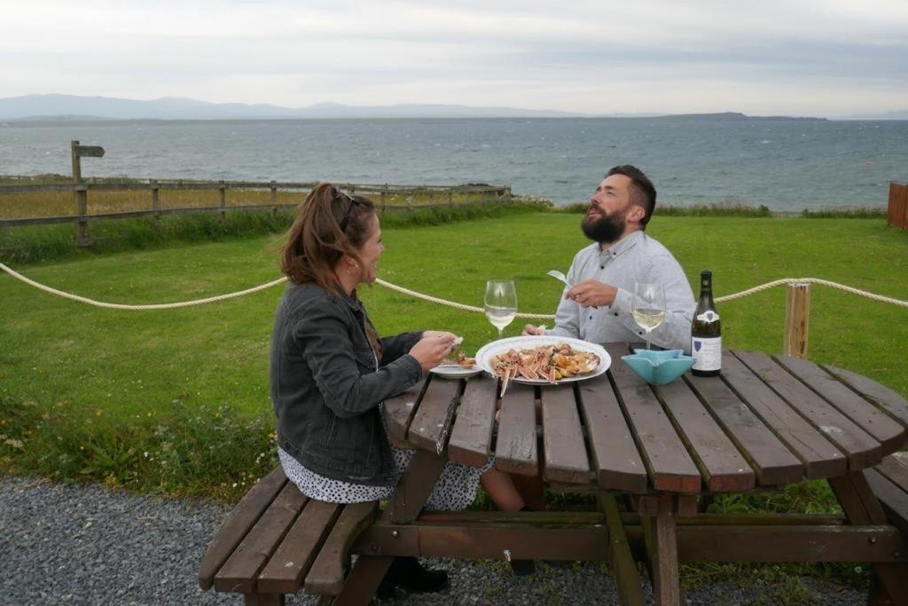 a man and woman sitting at a picnic table with a plate of food at Lochindaal Hotel in Port Charlotte