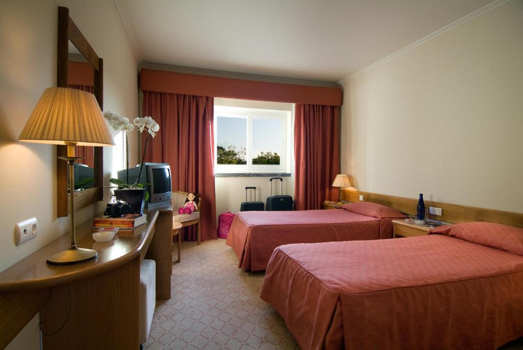 een hotelkamer met 2 bedden en een televisie bij Hotel Cruz Alta in Fátima