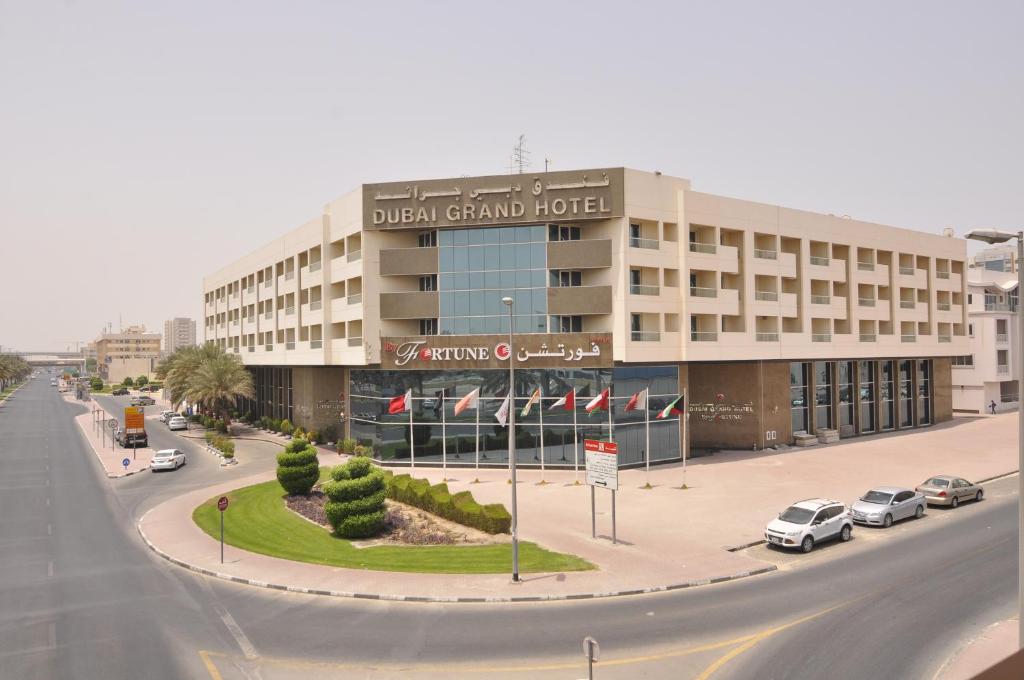 un gran edificio con coches aparcados frente a una calle en Dubai Grand Hotel by Fortune, Dubai Airport, en Dubái