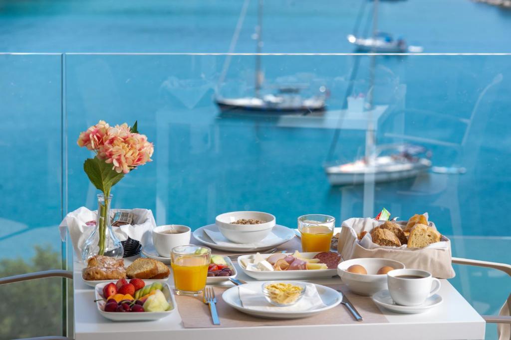 a breakfast table with food and drinks and a view of a harbor at Sivota Deamaris Luxury Boutique Hotel in Syvota