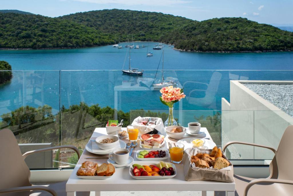 a table with breakfast food on a balcony with a view at Sivota Deamaris Luxury Boutique Hotel in Syvota