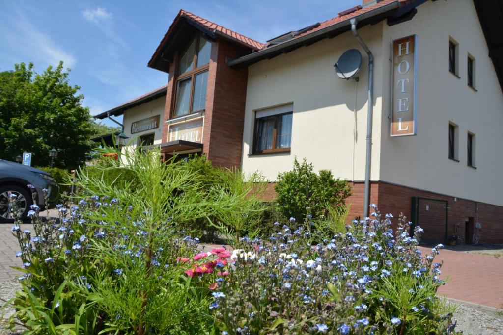 a garden in front of a house with flowers at Bestwaner Hotel in Bestensee