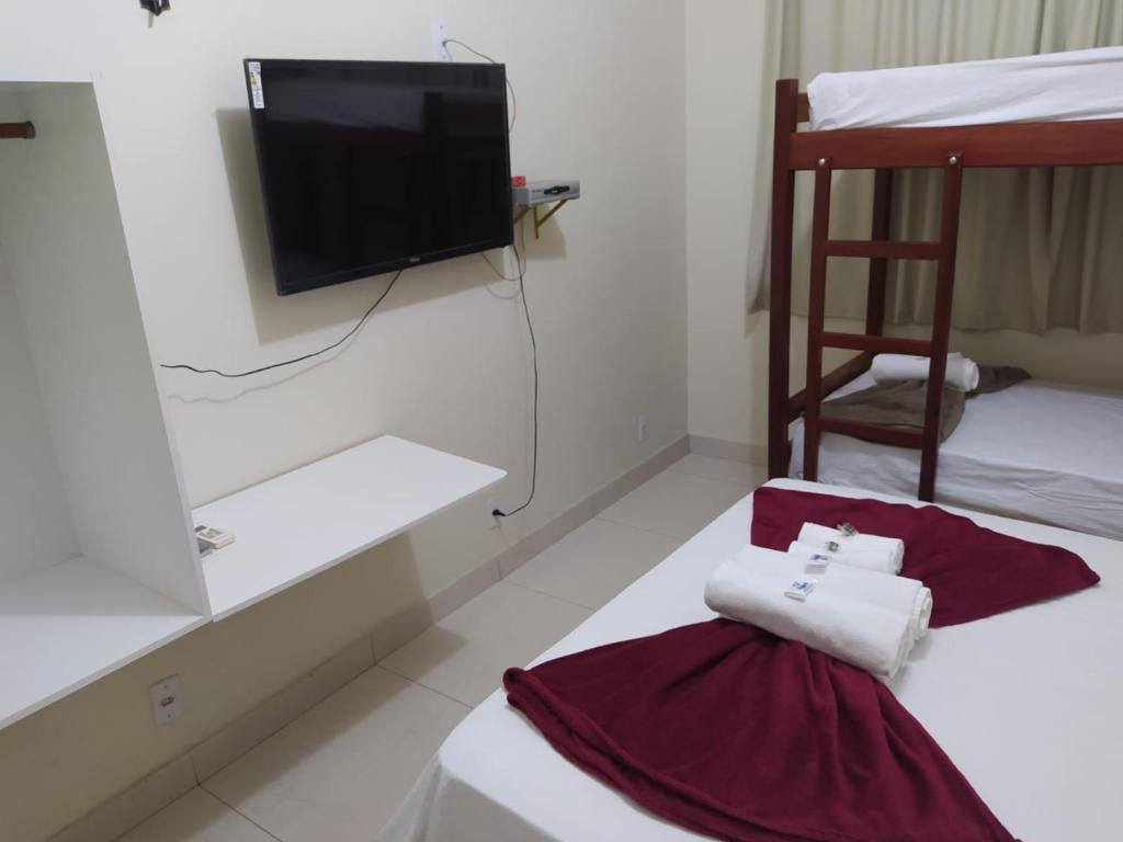 a bedroom with a tv and two bunk beds at Pousada da Praça in Ponte Alta do Norte