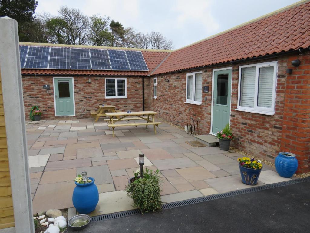 a patio with a picnic table and solar panels at The Stables At Eastmoor Farm in Bridlington