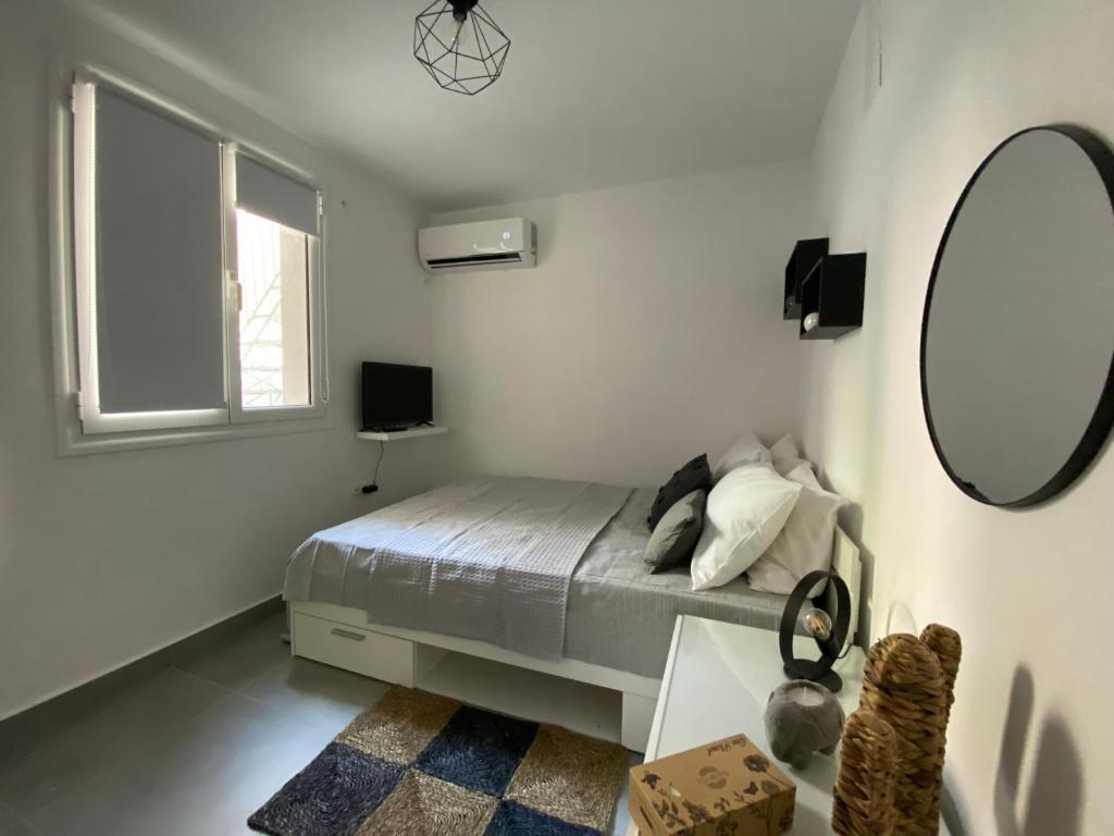 Habitación blanca con cama y espejo en Tiny Little House en Athens