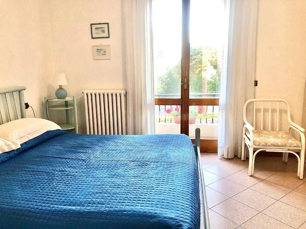 a bedroom with a blue bed and a chair and a window at B&B Curva della Palma in San Marino