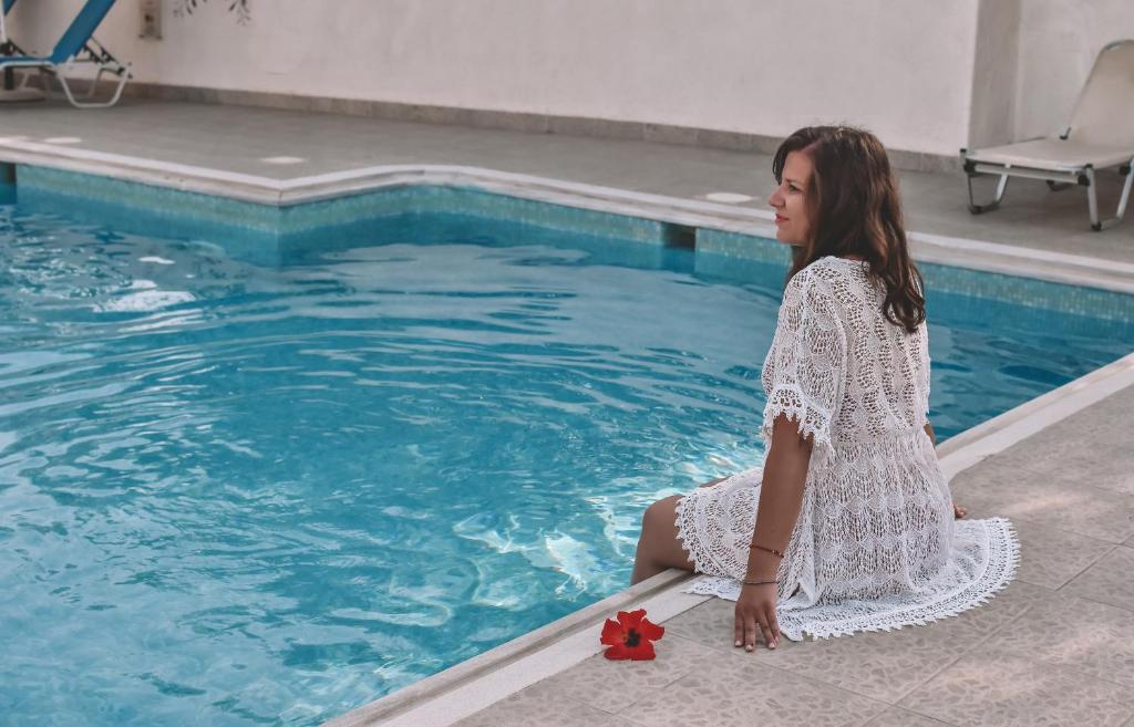 赫索尼索斯的住宿－Eleonora Αnissaras，坐在游泳池旁的年轻女人