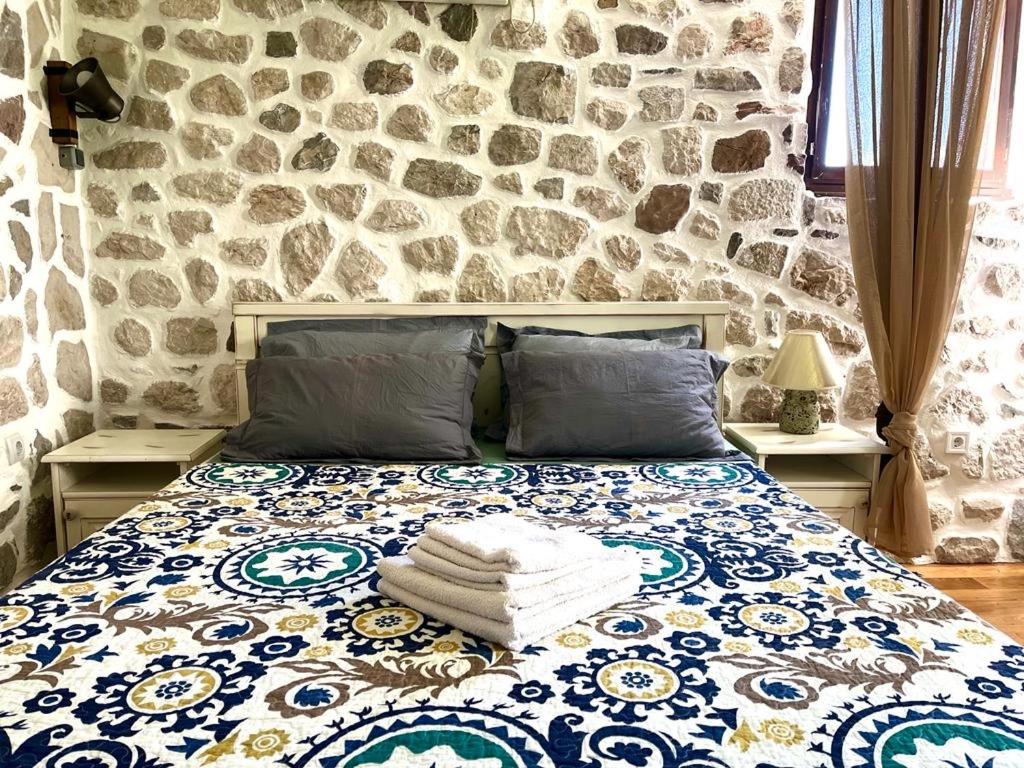 ein Schlafzimmer mit einem Bett mit einer Steinmauer in der Unterkunft Una apartments in Kotor