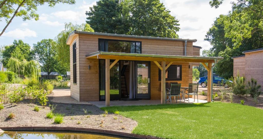 a tiny house with a patio and a pond at Fraai Tiny House aan het veluwemeer met uitzicht & veranda in Hulshorst