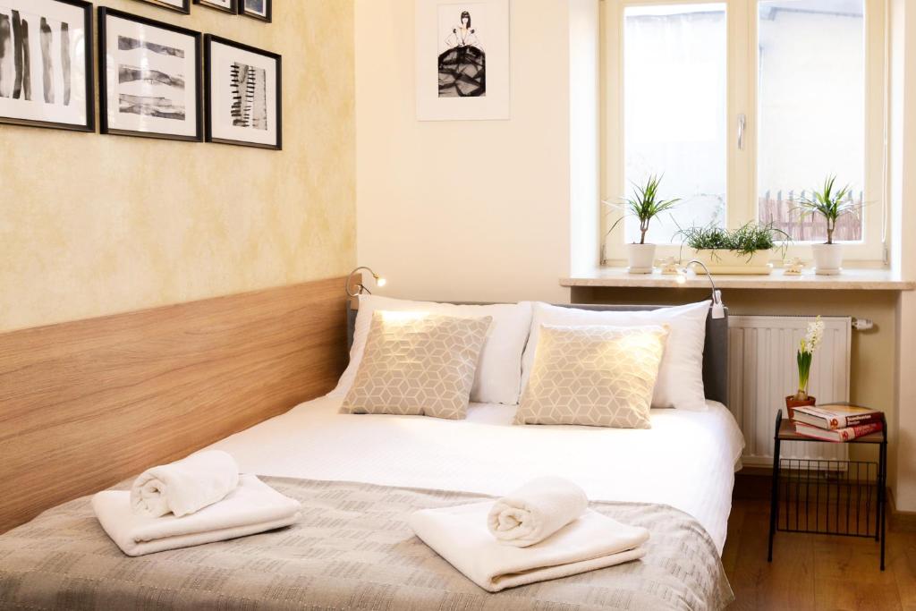 Neat double bed with patterned pillows, folded towels at foot of bed, window sill plants, soft lighting