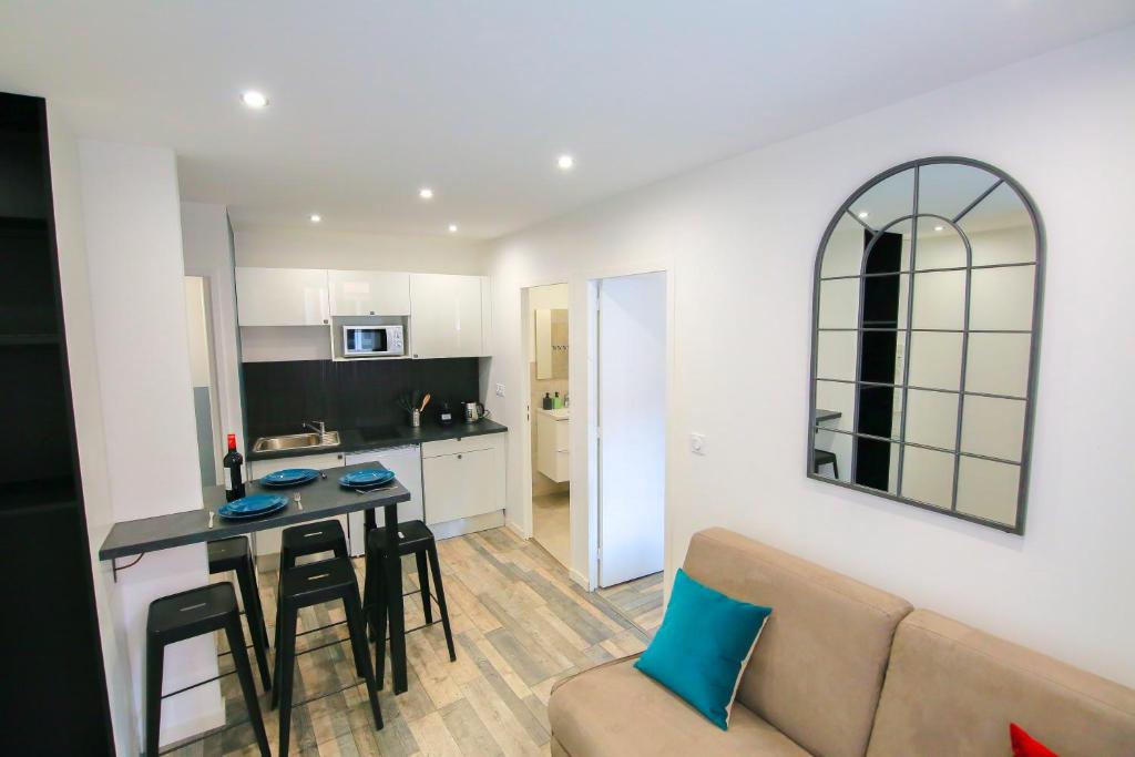 Il dispose d'une cuisine et d'un salon avec une table et un canapé. dans l'établissement La Montgolfière, T2 hypercentre chic et cosy, Wifi par SOVALFI, à Saint-Étienne