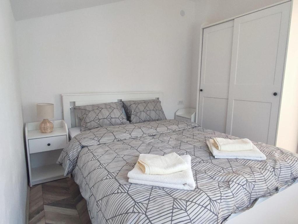 ein weißes Schlafzimmer mit einem Bett mit zwei Handtüchern darauf in der Unterkunft Apartman Flora Vrdnik in Vrdnik