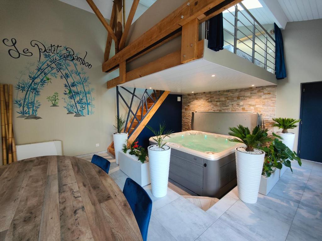 a hot tub in a room with a table and plants at Gîte Le Petit Bambou in Bressuire