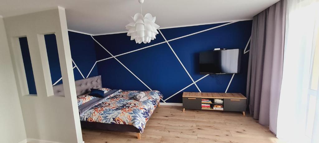 a bedroom with blue walls and a bed and a tv at Apartamenty Diamond na Sportowej in Tylicz