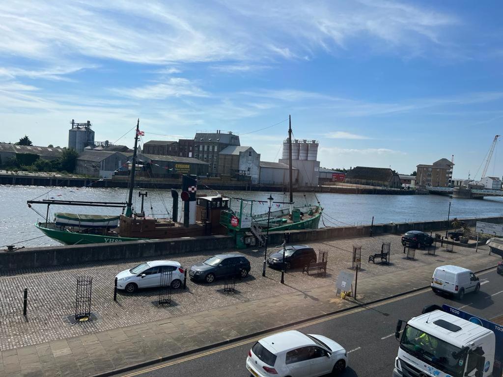 a group of cars parked next to a river with a boat at Spacious One Bedroom Flat with River View, 1E in Great Yarmouth