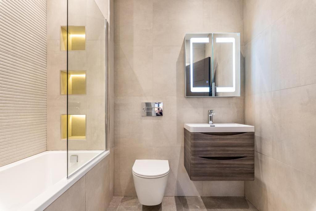 ein Badezimmer mit einem WC, einem Waschbecken und einem Spiegel in der Unterkunft Modern&Luxurios 1 Bed Apartment-Prime Location. in London
